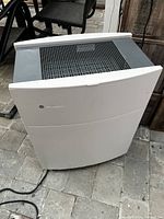 Front angled view showing curved white front panel, top vent, and power cord.