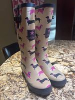 Side view of the beige Hawkins rain boots featuring black and pink wiener dog print with black sole and buckle strap