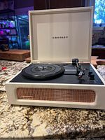 Front view of white Crosley turntable with lid open, showing platter, tonearm, and controls.