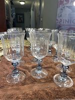 Front view showing multiple crystal goblets with blue stems arranged in rows on a towel, highlighting their fluted bowl shape and clear crystal height.