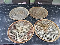 Top-down view of all four perforated pizza pans arranged on a table showing discoloration and use marks.