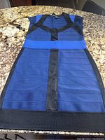 Full front view of blue and black bandage dress showing structured band design and short sleeves