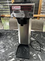 Front view of the Imperial commercial coffee maker showing stainless steel body, black drip tray, power cord, and front label with coffee cup image and 'Ready' indicator light.