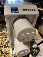 Side angle view of Kinetico Kube water filtration system showing two stacked white filter cartridges attached to the main housing unit, displaying Kube logo on the unit.