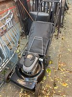 Full view of black Murray lawnmower showing attached mesh grass catcher bag and metal handle.