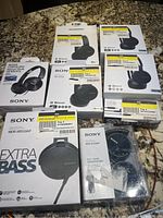 Photo showing 8 boxes of Sony headsets on tabletop, including MDR-XB550AP Extra Bass, WH-CH500 wireless, MDR-ZX310AP, and several similar boxes stacked