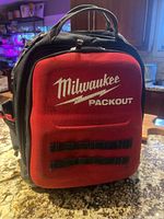 Front view of Milwaukee Packout Tool Backpack showing red front panel with logo and black sides