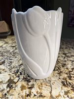 Front side view of the white ceramic tulip vase showing embossed tulip flower and leaf design.