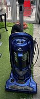 Full upright vacuum cleaner unit showing blue body, cord, and handle