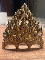 Front view of the brass napkin holder showing detailed Jerusalem cityscape with Menorah and enamel accents.