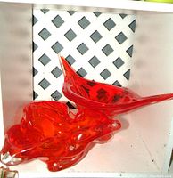 View of two deep orange Chalet art glass sculptures with lattice background, showing organic shapes and colors