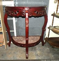 Front view of the two-tier marble and wood half moon table showing carved detail and legs