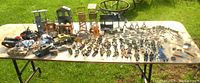 Full lot including fort pieces, vehicles, figures, and accessories laid out on table outdoors