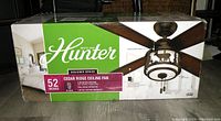 Box front showing brand Hunter, model Cedar Ridge Ceiling Fan with 52-inch size and pull chain operation.