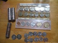 Top view showing two rolls of 50 cent pieces, three rolls of pennies, 125 year Confederation set in plastic display case, loose individual coins.