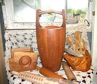 Overview of lot showing tall wooden pail with handle, wooden burl bowl with utensils, wooden canisters, and rolling pins on crocheted cloth.
