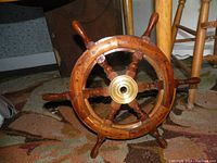 Front view of the wooden boat steering wheel showing all six handles and brass hub center.