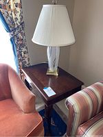 Full view of the wood end table with the glass lamp placed on top, showing the shade, lamp base, and table surface.