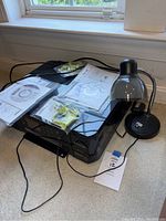 Epson XP-640 printer with manuals and discs on top, small black desk lamp to side on a dark surface