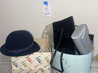 Photo of all items including various evening bags and a black woven hat on top of a labelled box