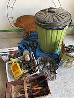 Full lot overview including copper pig decoration, metal wreath form, trash can, tarp, and assorted garden tools and hardware