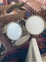 Kid size Ludwig drum set assembled with bass drum, two toms, and cymbal, all showing signs of use.