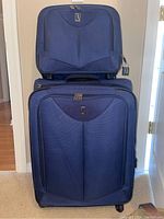 Front view of large and small navy blue Travelpro luggage pieces stacked together