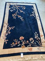 Full view of the navy and cream rug showing overall floral branch design and fringed ends.