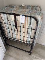 Folded Sears rollaway bed frame with attached mattress showing front and metal frame structure.