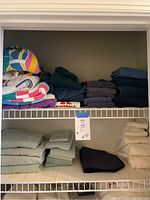 Two shelves with folded assorted towels in various colors and sizes.