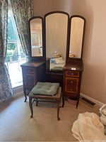 Full vanity with three-panel adjustable mirror and bench with cushion placed in bedroom corner.