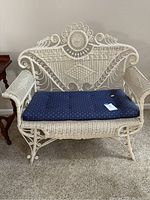 Full front view of the cream-colored vintage wicker loveseat with blue cushion featuring an anchor pattern, showing overall construction and condition.