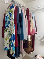 Assortment of women's dresses and sweaters of various colors hanging on a rack, showing variety and color range.