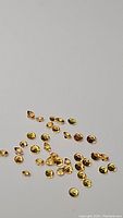 Photo of multiple small round and marquise yellow sapphires, diamond cut, scattered on a grey surface to showcase size and color.