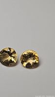 Close-up photo of two round golden citrine stones with diamond cut facets showing star pattern reflection