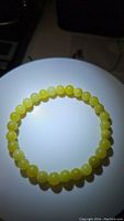 Photo of natural lemon jade stretchy bracelet arranged circularly on a white surface under lighting to show bead color and shine