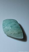 Photo showing blue amazonite kite-shaped gemstone with a checkerboard cut and visible surface inclusions and texture.