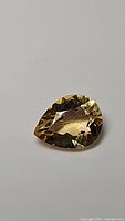 Clear image of pear-shaped golden citrine gemstone highlighting its clarity and faceting.
