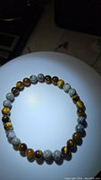 Full view of the stretchy bracelet showing natural map jasper and tiger's eye round beads in an alternating pattern under direct light.