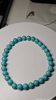 Photo shows natural turquoise bead bracelet laid flat, displaying uniform round beads in robin's egg blue with characteristic veining.