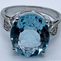 Front view showing oval aquamarine gemstone and silver band with accent stones.