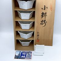 Five hexagonal porcelain bowls stacked in a wooden box with Japanese calligraphy on the lid, including small rectangular porcelain pieces and informational cards.