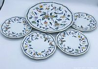 Five Narumi porcelain plates arranged with colorful floral designs, including one large and four smaller plates.