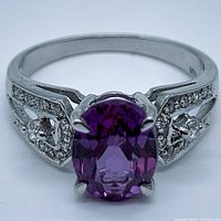 Close-up front view of oval purple amethyst ring with accent stones on band.