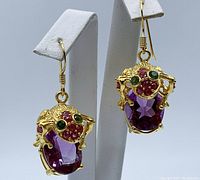 Front view of gold plated frog earrings on white display stand