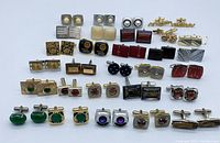 Another overhead view of 30 pairs of assorted cufflinks in different styles and colors showing gold-tone, silver-tone metals and inset stones.