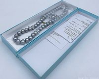 Set in open box showing dyed gray pearls on necklace and earrings with paperwork included.