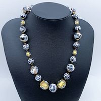 Front view of the multi-coloured beaded necklace on a black display bust, showing bead patterns and colors.