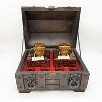 Front view of open rustic wooden box containing two square amber scotch decanters and four shot glasses with red felt lining