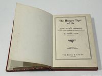 Open book showing title page with author Ruth Plumly Thompson and illustrator John R. Neill, published by The Reilly & Lee Co.